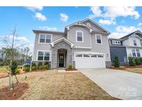 Two-story home showcasing gray siding, stone accents, a two-car garage and a well-manicured lawn against a bright blue sky at 9934 Cask Way, Huntersville, NC 28078