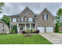 Beautiful two-story brick home with a well-manicured lawn, front porch, attached two-car garage, and decorative fountain at 10304 Squires Way # 18, Cornelius, NC 28031