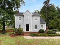 Charming two-story home featuring a well-maintained front yard with mature trees and a classic black front door at 124 Creek Hollow Trl, Belmont, NC 28012
