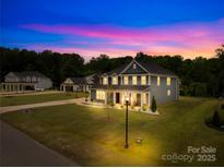 Beautiful two-story home featuring a well-manicured lawn, illuminated by outdoor lighting at dusk at 126 Still Creek Dr, Mooresville, NC 28115