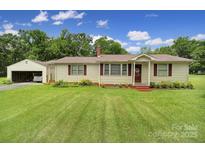 Charming single-story home with a well-maintained lawn, brick details, and an adjacent detached garage at 2084 Old Evans Cir, Lancaster, SC 29720