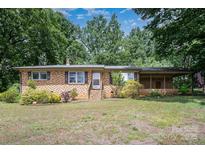 Charming brick home with covered porch and mature trees on a sunny day at 2631 Ivey Church Rd, Lincolnton, NC 28092
