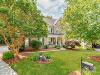 Beautiful two-story brick home featuring manicured landscaping and a welcoming front porch with rocking chairs at 537 Montgrove Nw Pl, Concord, NC 28027