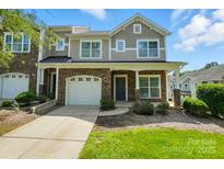 Charming townhome featuring a stone facade, attached garage, and well-maintained front lawn at 6333 Cory Bret Ln, Charlotte, NC 28278