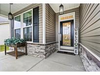 Charming front porch with stone accents, black shutters, and a welcoming entrance door at 7809 Creek Park Dr, Denver, NC 28037