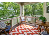 Inviting covered porch with wood furniture and a red and white patterned rug overlooking the trees at 915 Northeast Dr # 15, Davidson, NC 28036