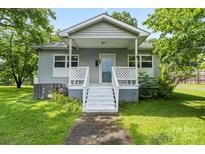 Charming home featuring a quaint porch, light gray siding, complemented by a well-maintained lawn and mature trees at 935 Church St, Kings Mountain, NC 28086