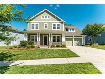 Inviting two-story home with a charming front porch, manicured lawn, and attached two-car garage at 11324 Fullerton Place Nw Dr, Huntersville, NC 28078