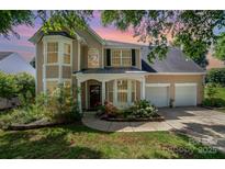Charming tan home featuring a two-car garage, lush landscaping, and a welcoming front entrance at 11802 Fox Glen Rd, Charlotte, NC 28269