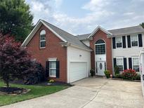 Charming two-story home boasts a brick and vinyl exterior, a manicured lawn, and an attached two-car garage at 13528 Philip Michael Rd, Huntersville, NC 28078
