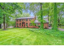 Charming brick home with lush green lawn and mature trees, creating a serene and inviting curb appeal at 16512 Kimbolten Dr, Huntersville, NC 28078
