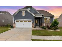 Charming exterior with blue siding, stone accents, manicured lawn, and two car garage at 1663 Tranquility Blvd, Lancaster, SC 29720