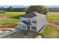Newly built two-story home featuring gray siding, black roof, and a welcoming covered entryway at 21047 Running Creek Dr # 9, Locust, NC 28097