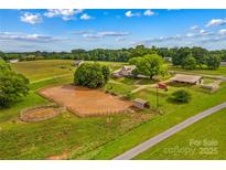 Expansive horse property featuring an arena and outbuildings, set amid lush greenery under a partly cloudy sky at 296 Hicks Creek Rd, Troutman, NC 28166