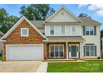 Charming two-story home featuring stone accents, a two-car garage, and a welcoming front porch at 3005 Streamlet Way, Monroe, NC 28110