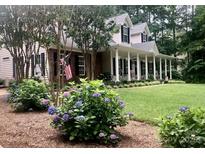 Charming home featuring a covered front porch with white columns, black shutters, and an American flag at 390 Robinson Rd, Mooresville, NC 28117