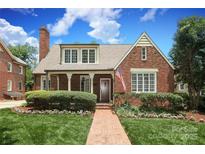 Charming brick home with manicured lawn, brick walkway, and inviting front entrance under a partly cloudy sky at 1021 Isleworth Ave, Charlotte, NC 28203