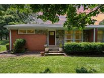Charming brick and stone home with a well-manicured lawn, inviting entrance, and beautiful landscaping at 4232 Randolph Rd, Charlotte, NC 28211