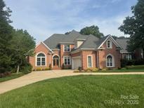 Stately red brick home features a well-manicured lawn, mature trees, and a welcoming double-door entryway at 4740 Myers Ln, Harrisburg, NC 28075