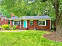 Charming red brick home with a vibrant teal front door and lush green lawn at 4906 Charleston Dr, Charlotte, NC 28212