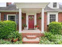 Welcoming red front door with a wreath, flanked by potted plants and manicured bushes at 81 21St Nw Ave, Hickory, NC 28601