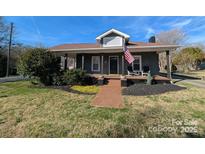 Charming home with a cozy front porch, manicured landscaping, and patriotic American flag display at 101 Sunset Dr, Stanley, NC 28164