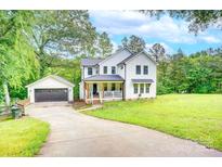 Charming two-story home with a welcoming front porch, detached garage, and a spacious, well-manicured lawn at 1062 Willow Ridge Ln, Fort Mill, SC 29707