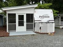 Charming camper with screened porch and white lattice skirting providing a cozy and private outdoor living space at 107 Pine St, New London, NC 28127