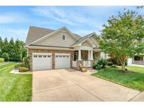 Charming home featuring a stone facade, two-car garage, manicured lawn, and a welcoming front porch at 12910 Meetinghouse Dr, Cornelius, NC 28031