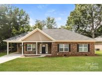 Charming brick home featuring a well-maintained lawn, covered front porch, and inviting curb appeal at 153 Ole Eastpointe Dr, York, SC 29745