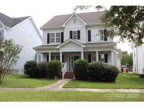 Charming two-story home with a welcoming front porch, manicured bushes and black shutters at 19834 Davidson Concord Rd, Davidson, NC 28036