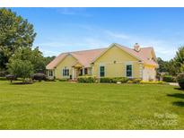 Charming yellow single-story home with a lush green lawn and well-maintained landscaping under a clear blue sky at 205 Harwell Rd, Mooresville, NC 28117