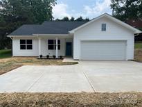 Charming single-story home boasting a white exterior, well-manicured lawn, and an attached garage at 210 Johnson St, Troutman, NC 28116