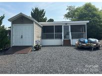 Charming home exterior featuring a screened-in porch, shed, and boats for outdoor recreation at 217 Badin View Dr # B257, New London, NC 28127