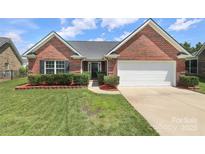 Charming single-story red brick home featuring manicured lawn, tasteful landscaping and a two car garage at 3523 Brickwood Cir, Midland, NC 28107