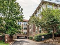 Condo exterior features brick accents, drive-under parking, and mature landscaping at 404 N Laurel Ave # 11, Charlotte, NC 28204