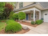 Charming front porch with stone accents, a blue front door, and manicured landscaping at 7101 Weavers Run, Cramerton, NC 28032