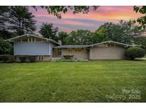 Charming single-story home featuring a lush green lawn and mature landscaping with a mix of brick and siding at 985 Needmore Rd, Woodleaf, NC 27054
