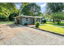 Charming home with gray painted brick and a gravel driveway framed by mature trees in a large yard at 112 Lineberger St, Stanley, NC 28164