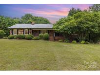 Charming brick ranch home featuring a well-manicured lawn and mature trees for added privacy at 115 Turner St, Lincolnton, NC 28092