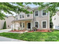 Charming two-story home with a well-manicured lawn, flowers, and a cozy front porch, enhancing its curb appeal at 14904 Rosemary Way Dr, Huntersville, NC 28078