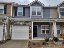 Charming townhouse with a stone facade, a white garage door, and a welcoming front porch at 15239 Wrights Crossing Dr, Charlotte, NC 28278