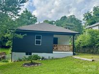 Charming home featuring a decorative wood porch, black siding, and a well-maintained front yard at 16 Cherry St, Albemarle, NC 28001