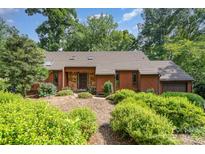 Charming single-story home featuring wood and stone accents with lush landscaping and mature trees in the front yard at 1601 Wandering Way Dr, Charlotte, NC 28226