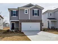 Two-story home with gray siding, brick accents, a two-car garage, and a neatly paved driveway at 213 J.P. Dr, Albemarle, NC 28001