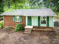 Charming single-story home with brick and siding, and green shutters nestled among mature trees at 24 19Th Nw St, Hickory, NC 28601