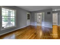 A bright living room offers gleaming hardwood floors, neutral paint, and a doorway leading into another room at 24 19Th Nw St, Hickory, NC 28601
