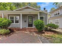 Charming gray home featuring manicured landscaping, a brick walkway and welcoming front porch at 2813 Hilliard Dr, Charlotte, NC 28205