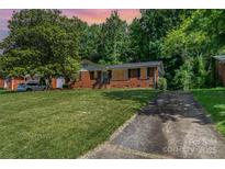 Charming brick home with mature trees, a well-maintained lawn, and a private driveway at 3939 Sheffield Dr, Charlotte, NC 28205