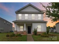 Charming two-story home featuring a covered porch with stone accents and well-manicured landscaping at 422 Nixon Rd, Belmont, NC 28012